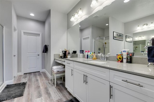 bathroom with wood-type flooring, vanity, and a shower with shower door