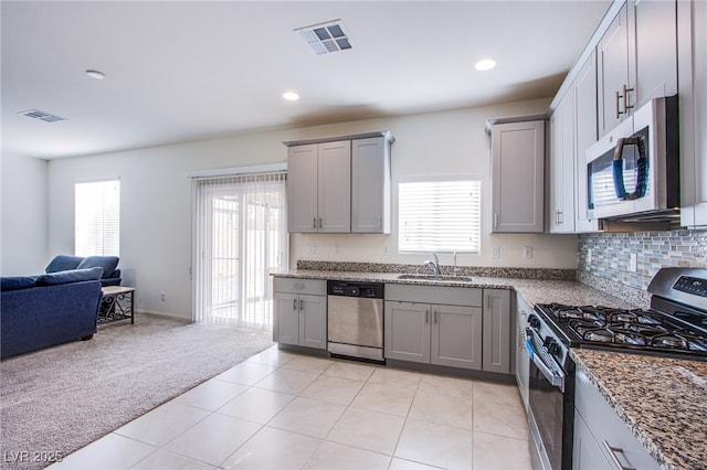 kitchen with sink, gray cabinets, stone countertops, light colored carpet, and stainless steel appliances