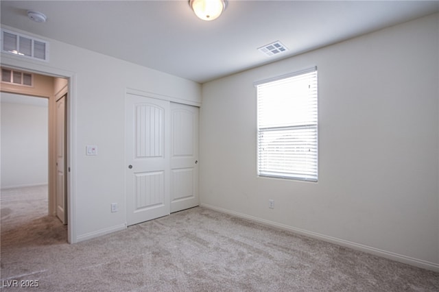 unfurnished bedroom featuring a closet and light colored carpet