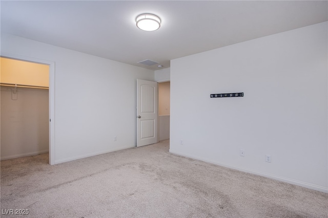 unfurnished bedroom featuring a walk in closet, light colored carpet, and a closet