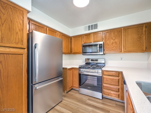 kitchen with sink, stainless steel appliances, and light hardwood / wood-style flooring