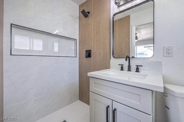 bathroom with tiled shower, vanity, and toilet