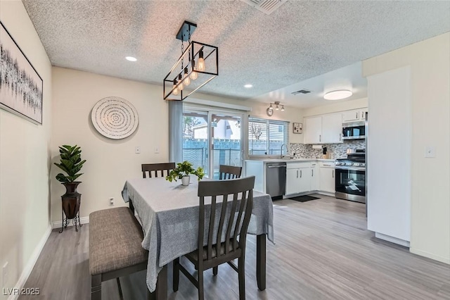 dining room featuring a textured ceiling, light wood-type flooring, and sink