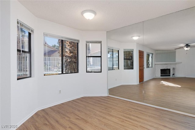 unfurnished living room featuring ceiling fan, a textured ceiling, and light hardwood / wood-style flooring