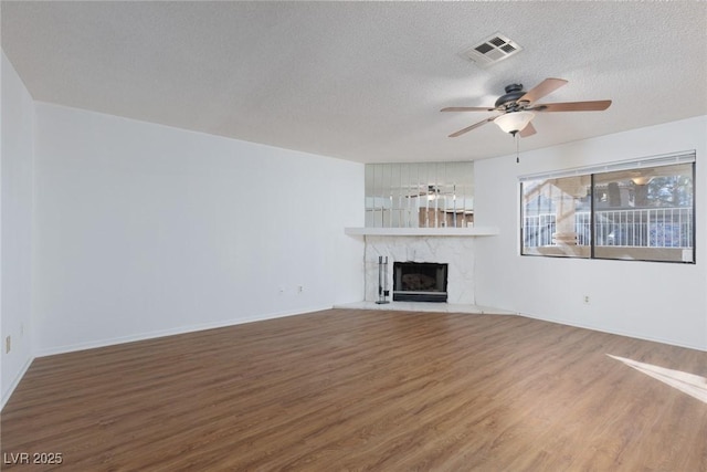 unfurnished living room with a textured ceiling, ceiling fan, a high end fireplace, and wood-type flooring