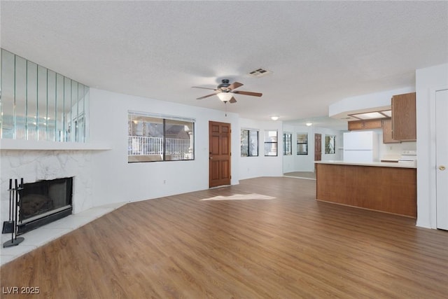 unfurnished living room with ceiling fan, a textured ceiling, and light hardwood / wood-style flooring