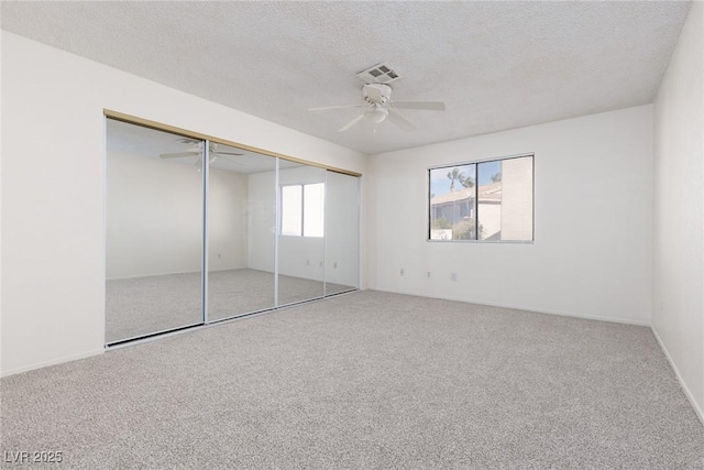 unfurnished bedroom featuring a textured ceiling, ceiling fan, a closet, and carpet floors