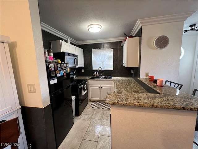 kitchen featuring kitchen peninsula, a kitchen breakfast bar, black appliances, sink, and white cabinetry