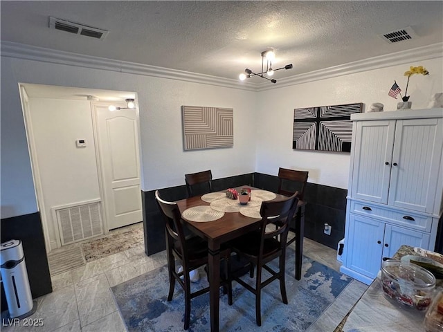 dining area with a notable chandelier, ornamental molding, and a textured ceiling