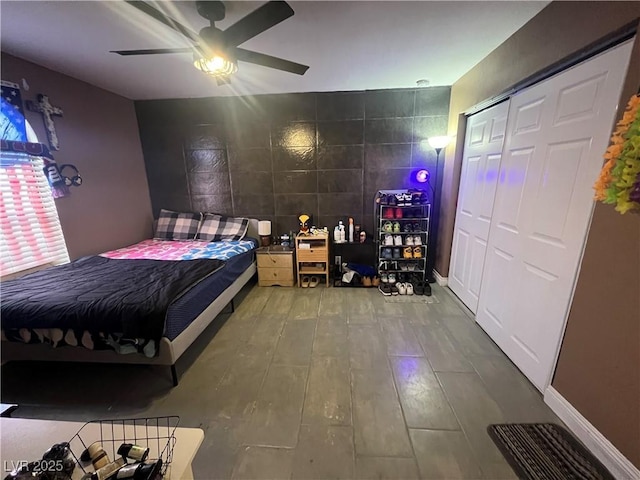 bedroom with hardwood / wood-style flooring, ceiling fan, tile walls, and a closet