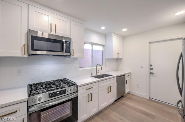 kitchen featuring sink, white cabinets, stainless steel appliances, and light hardwood / wood-style floors