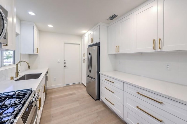 kitchen with white cabinets, sink, light wood-type flooring, and stainless steel appliances