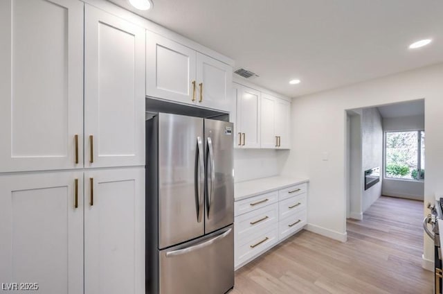 kitchen with white cabinets, light wood-type flooring, and appliances with stainless steel finishes