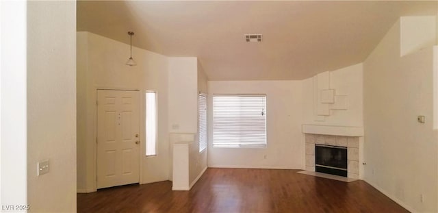 entrance foyer with a healthy amount of sunlight, vaulted ceiling, a fireplace, and dark wood-type flooring