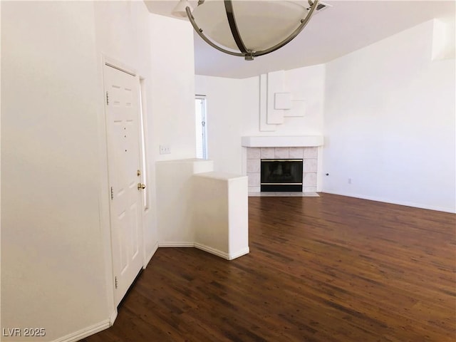 unfurnished living room featuring a tile fireplace and dark wood-type flooring