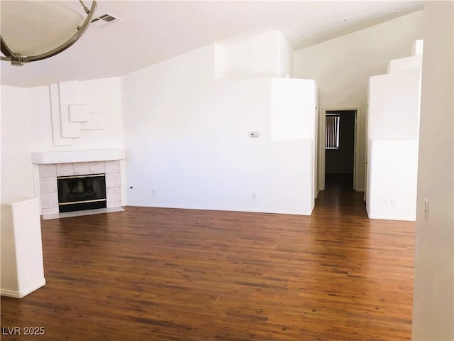 unfurnished living room with a tiled fireplace and dark wood-type flooring