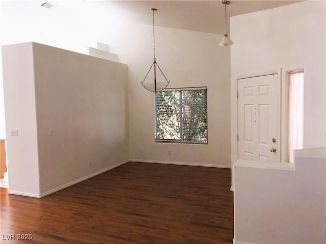 unfurnished dining area featuring dark hardwood / wood-style flooring and a towering ceiling