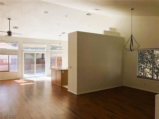 interior space with ceiling fan with notable chandelier, a wealth of natural light, and dark wood-type flooring