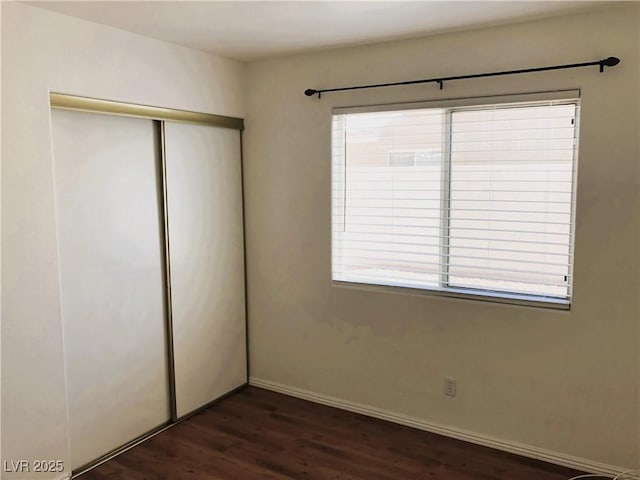 unfurnished bedroom featuring dark wood-type flooring and a closet