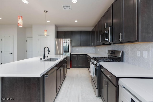 kitchen with backsplash, decorative light fixtures, sink, and appliances with stainless steel finishes