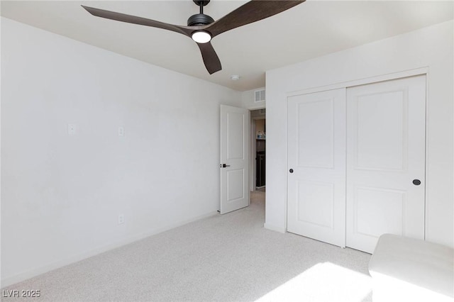 unfurnished bedroom featuring ceiling fan, light colored carpet, and a closet