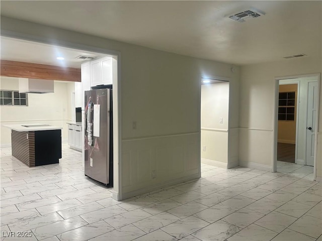 kitchen with white cabinets, a center island, black electric cooktop, and stainless steel refrigerator