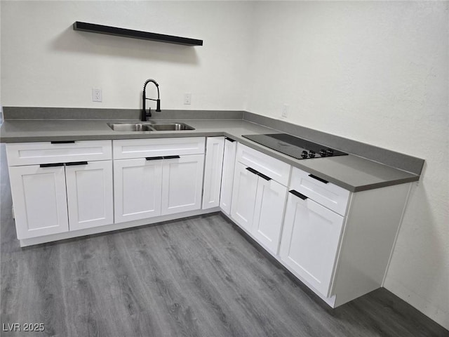 kitchen with white cabinets, dark hardwood / wood-style flooring, black electric stovetop, and sink