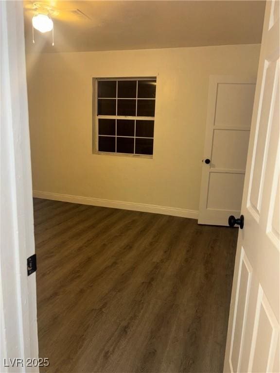 empty room with ceiling fan and dark wood-type flooring