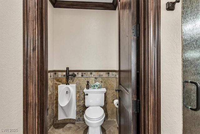 bathroom featuring toilet, ornamental molding, and tile walls