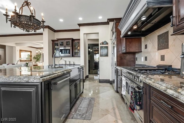 kitchen featuring light stone countertops, an inviting chandelier, ventilation hood, a center island with sink, and appliances with stainless steel finishes