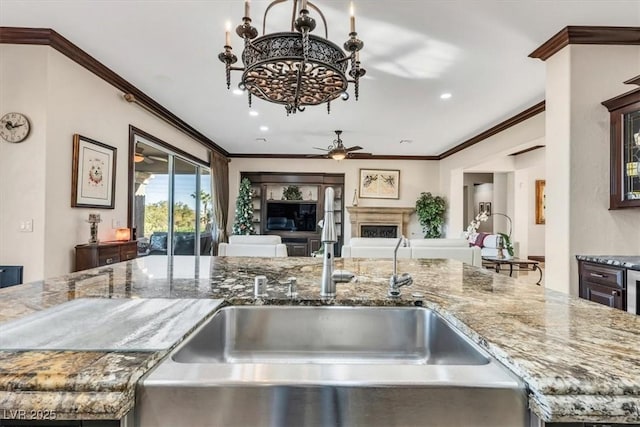 kitchen with light stone counters, sink, and crown molding