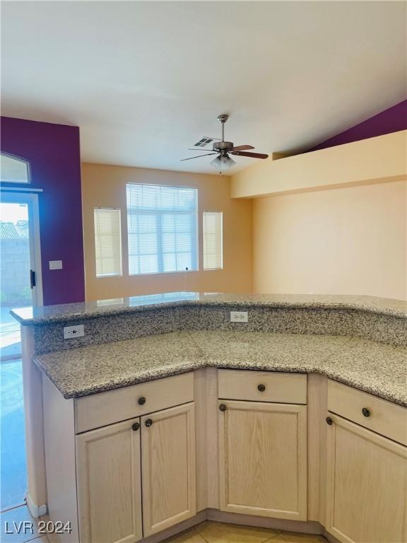 kitchen with ceiling fan and light stone countertops