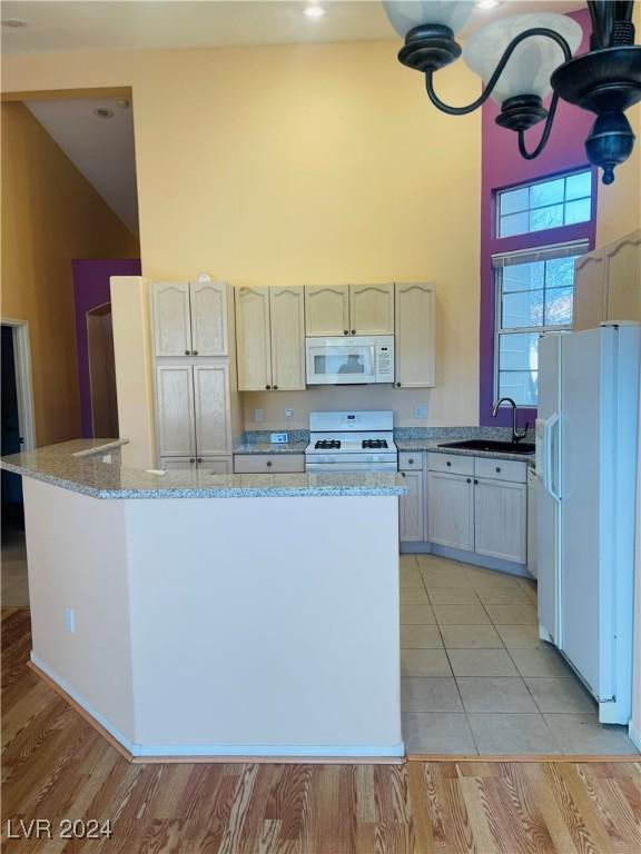 kitchen with light stone counters, white appliances, high vaulted ceiling, and sink