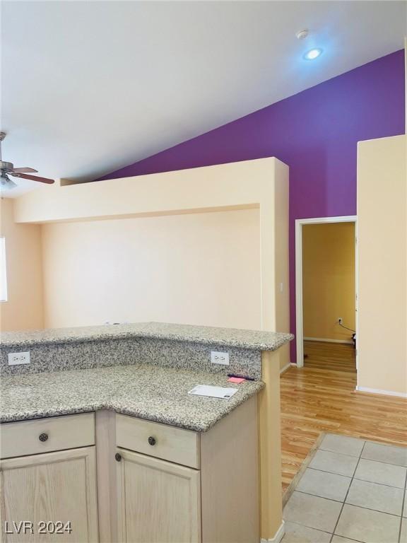 kitchen featuring light tile patterned floors, ceiling fan, light stone countertops, light brown cabinetry, and vaulted ceiling