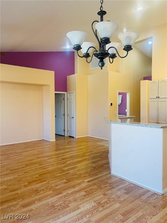 interior space with high vaulted ceiling, light wood-type flooring, and a chandelier