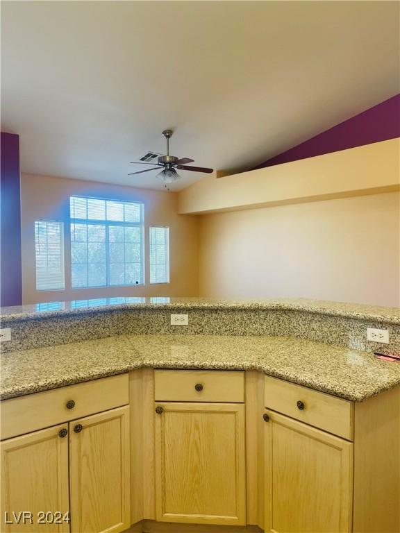 kitchen featuring light stone counters, ceiling fan, light brown cabinetry, and kitchen peninsula