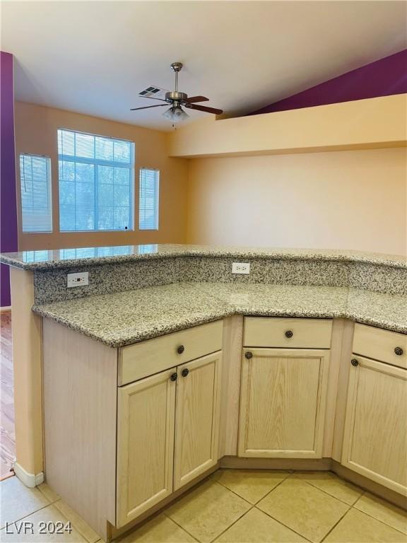 kitchen featuring ceiling fan, light brown cabinetry, light stone countertops, and light tile patterned floors