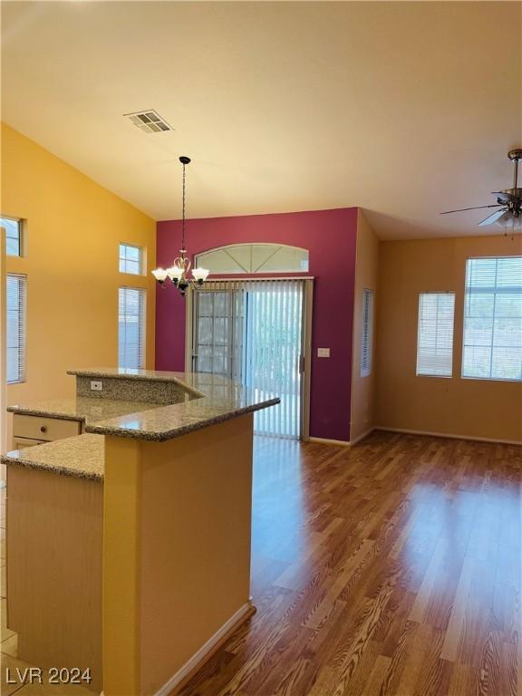 kitchen featuring hanging light fixtures, light stone countertops, dark hardwood / wood-style floors, and a healthy amount of sunlight