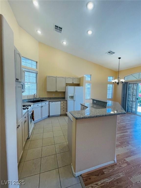 kitchen with white appliances, healthy amount of natural light, a sink, a chandelier, and recessed lighting