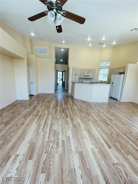 unfurnished living room with light wood-type flooring, a ceiling fan, and recessed lighting