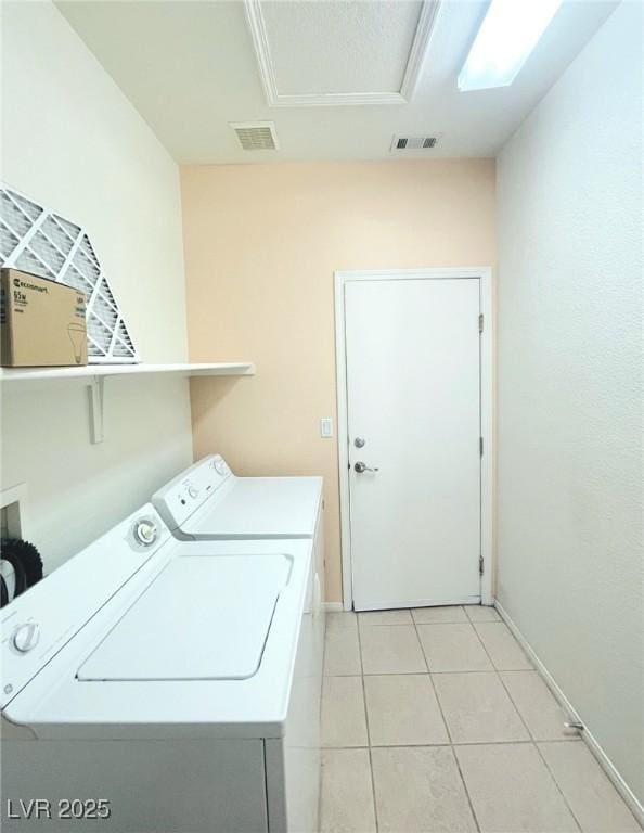 clothes washing area featuring separate washer and dryer, light tile patterned floors, and baseboards