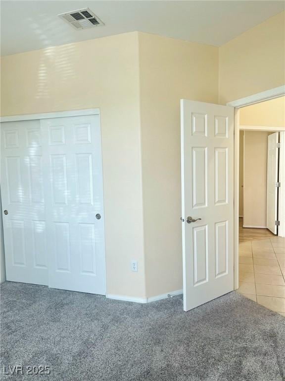 unfurnished bedroom featuring light carpet, baseboards, and light tile patterned floors