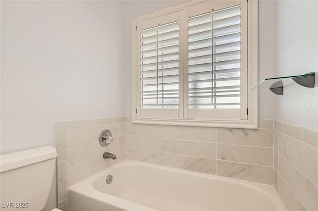 bathroom featuring toilet and a tub to relax in