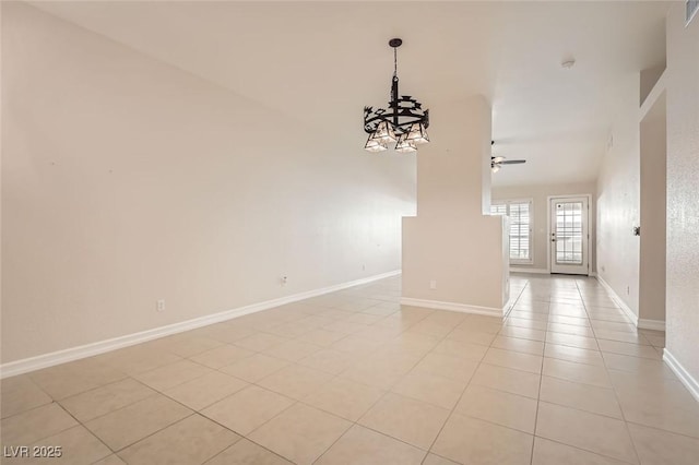 tiled spare room featuring ceiling fan with notable chandelier