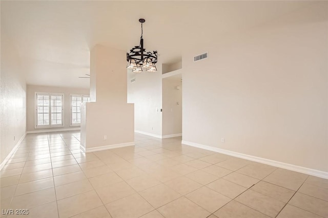 spare room with ceiling fan with notable chandelier and light tile patterned floors