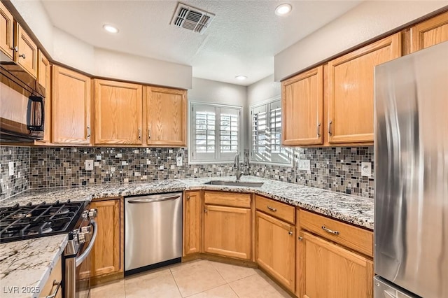 kitchen with decorative backsplash, appliances with stainless steel finishes, light tile patterned floors, and sink