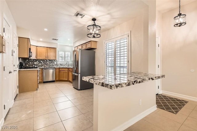 kitchen with decorative backsplash, pendant lighting, stainless steel appliances, and a notable chandelier