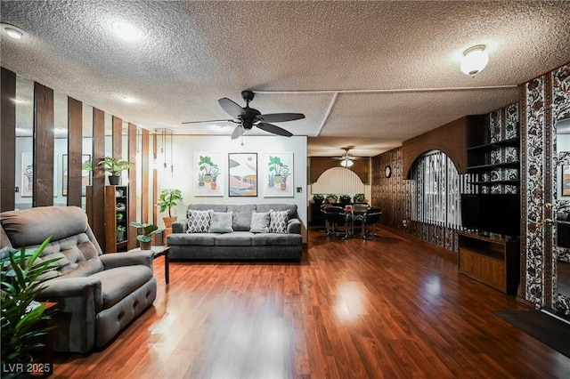 living room featuring a textured ceiling, ceiling fan, and dark hardwood / wood-style floors