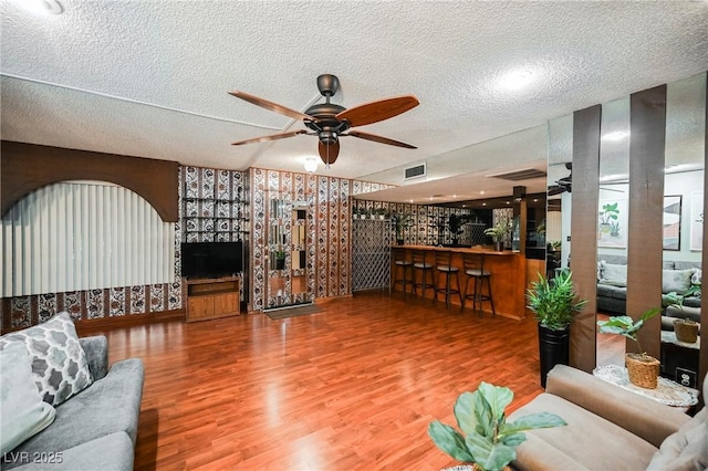 living room featuring hardwood / wood-style flooring, ceiling fan, and a textured ceiling