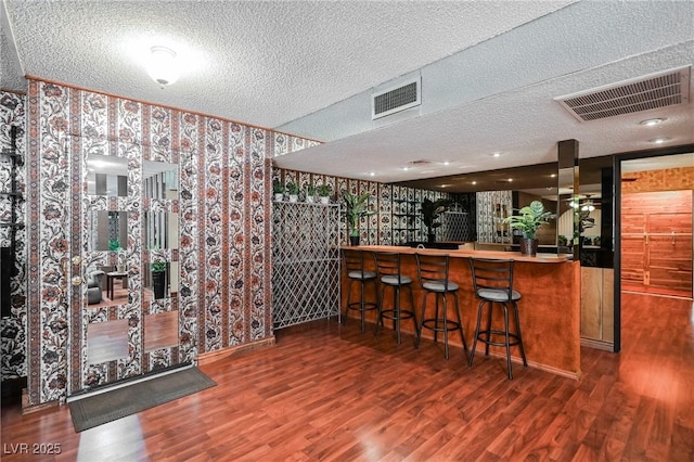 bar with a textured ceiling and dark hardwood / wood-style flooring